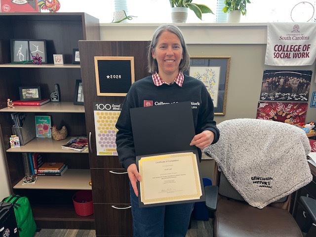 Woman standing in office holding a certificate.