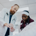 man teaches nursing student how to place IV