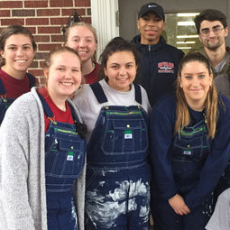 Students show off their paint covered overalls after a rewarding day of volunteer work.