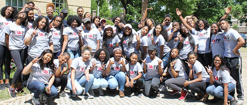 Mapp mentors pose in front of a campus building.