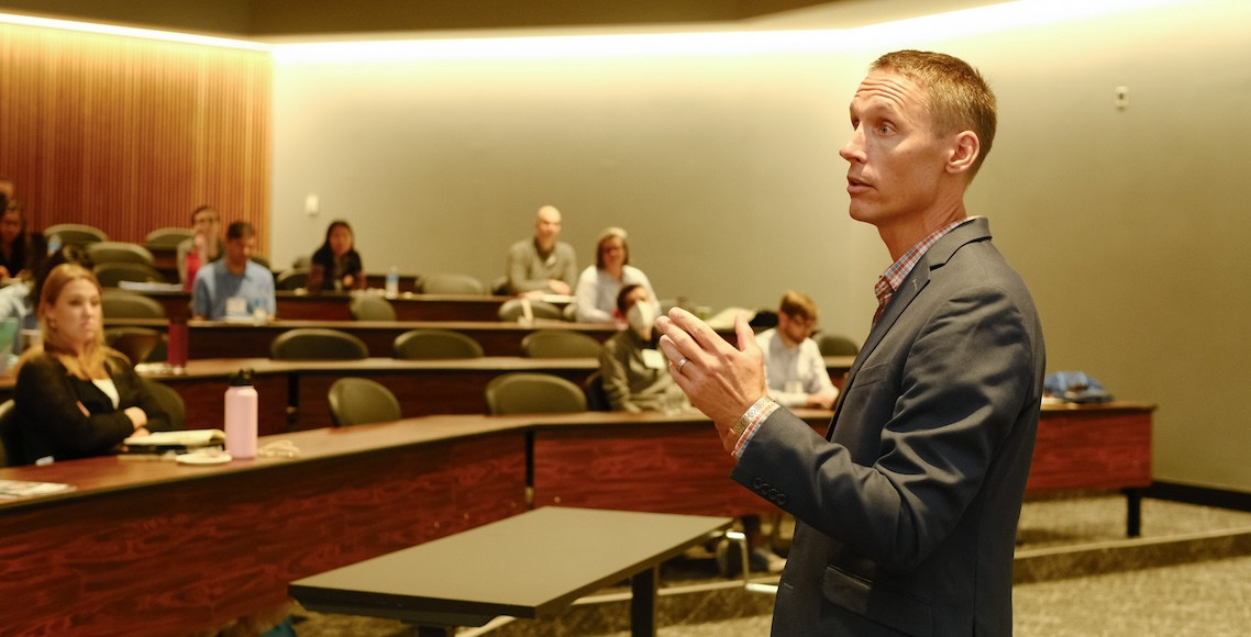 Presenter speaking to a group of research professionals in a large lecture room