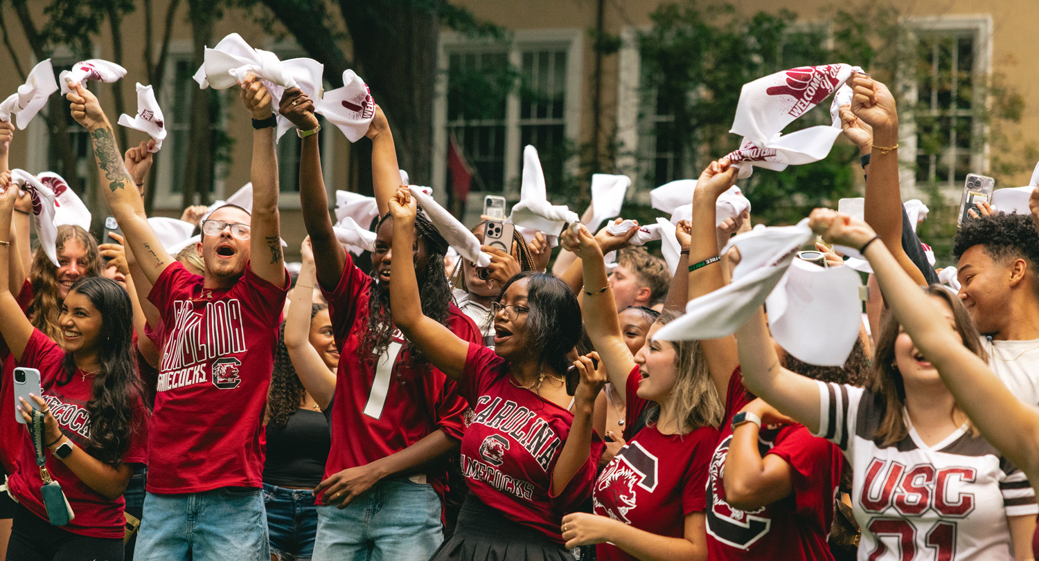 Students gathered together with their arms raised at an event on Greene Street.