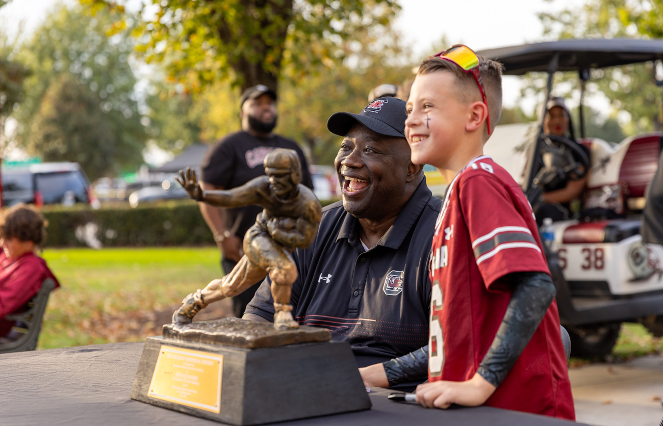 George Rogers and a young fan pose with the Heisman Trophy