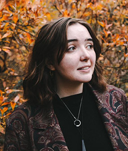 woman smiling outside with paid jacket on