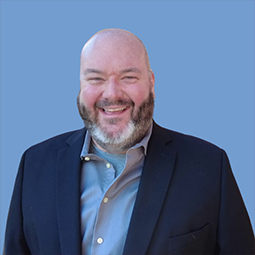 a man smiling with a blue suit on