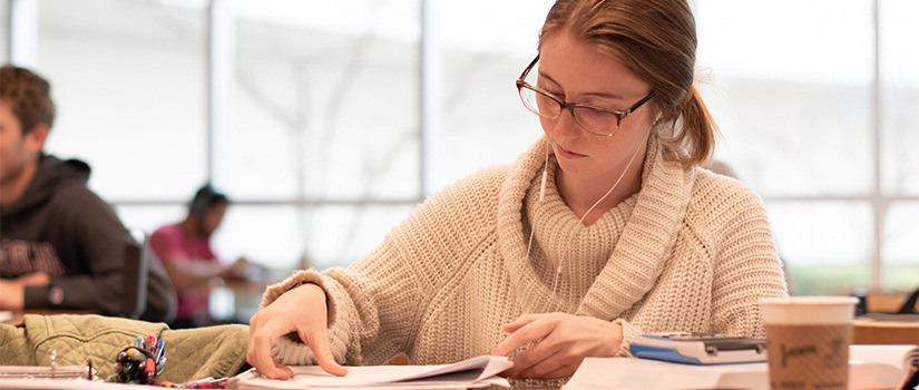 female student studies with headphones in