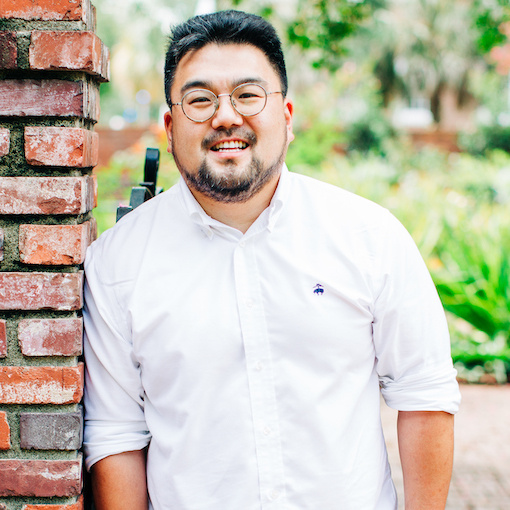 Smiling man with short black hair and glasses, wearing a white dress shirt