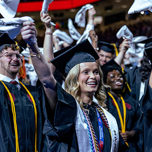 Woman in cap and gown waving towel at graduation ceremony