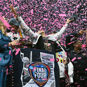 woman stands in a shower of confetti with hands raised to the ceiling