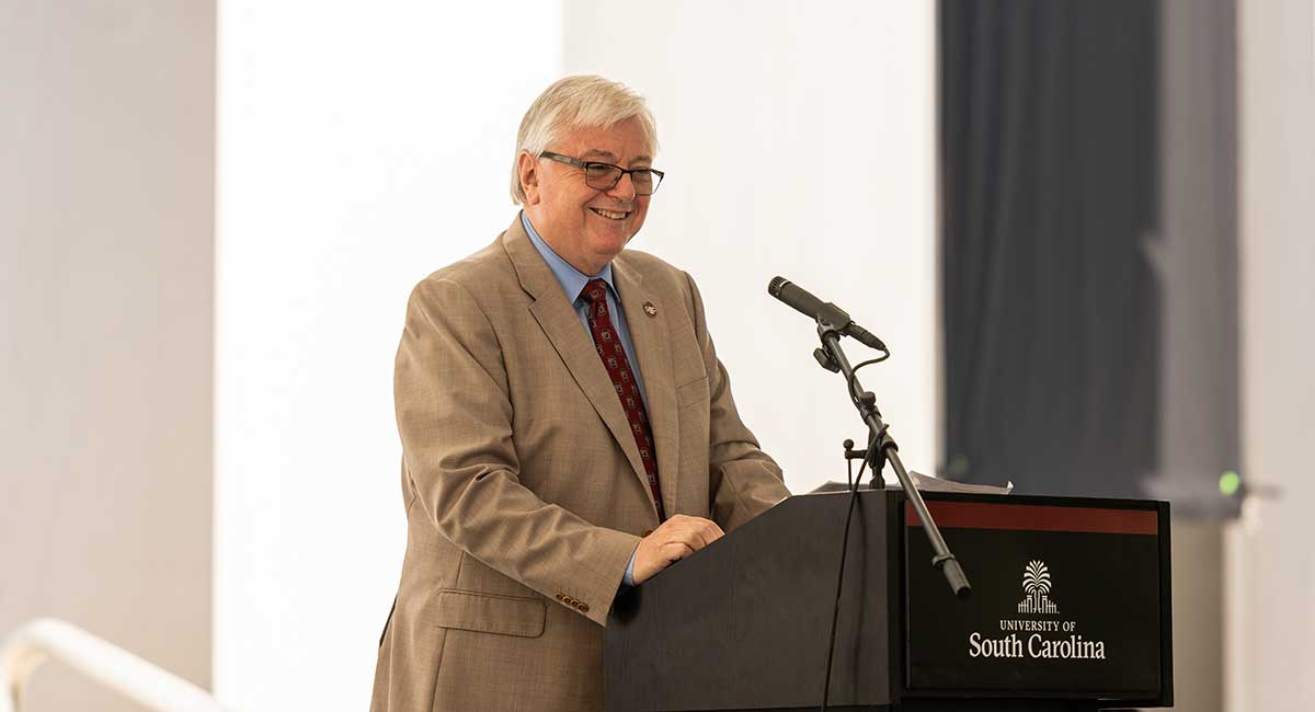 USC President Michael Amiridis stands at podium in front of USC's Swearingen Engineering Center.